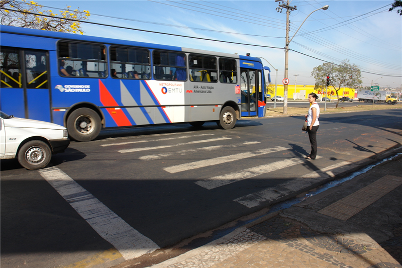 Pedestre fica impedida de atravessar por veículos que atravessam no sinal vermelho